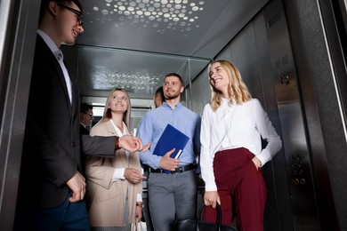 Group of office workers talking in modern elevator