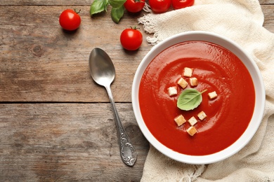 Photo of Bowl with fresh homemade tomato soup and space for text on wooden table, top view