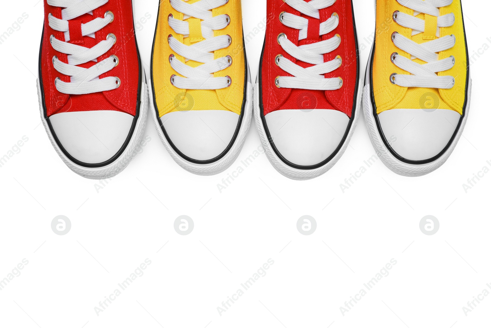 Photo of Yellow and red classic old school sneakers isolated on white, top view