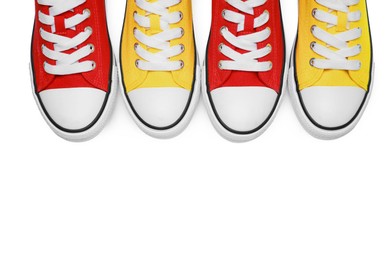 Photo of Yellow and red classic old school sneakers isolated on white, top view