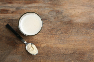 Protein shake and powder on wooden table, flat lay. Space for text