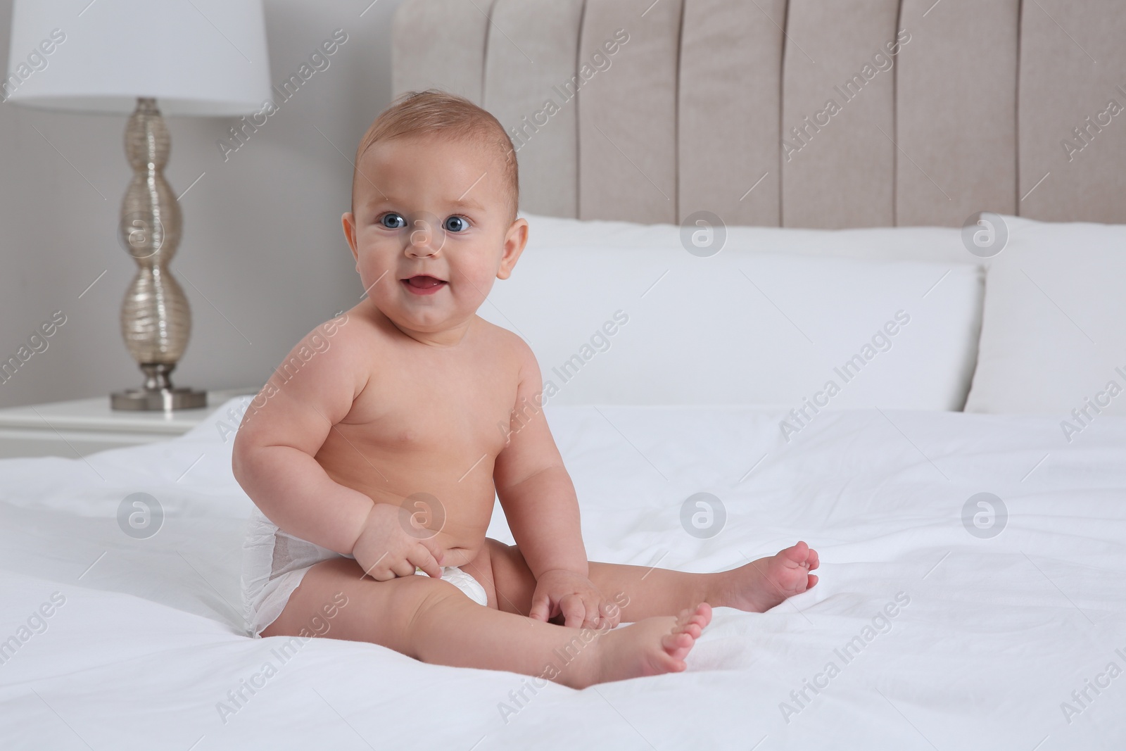 Photo of Cute baby in dry soft diaper on white bed at home