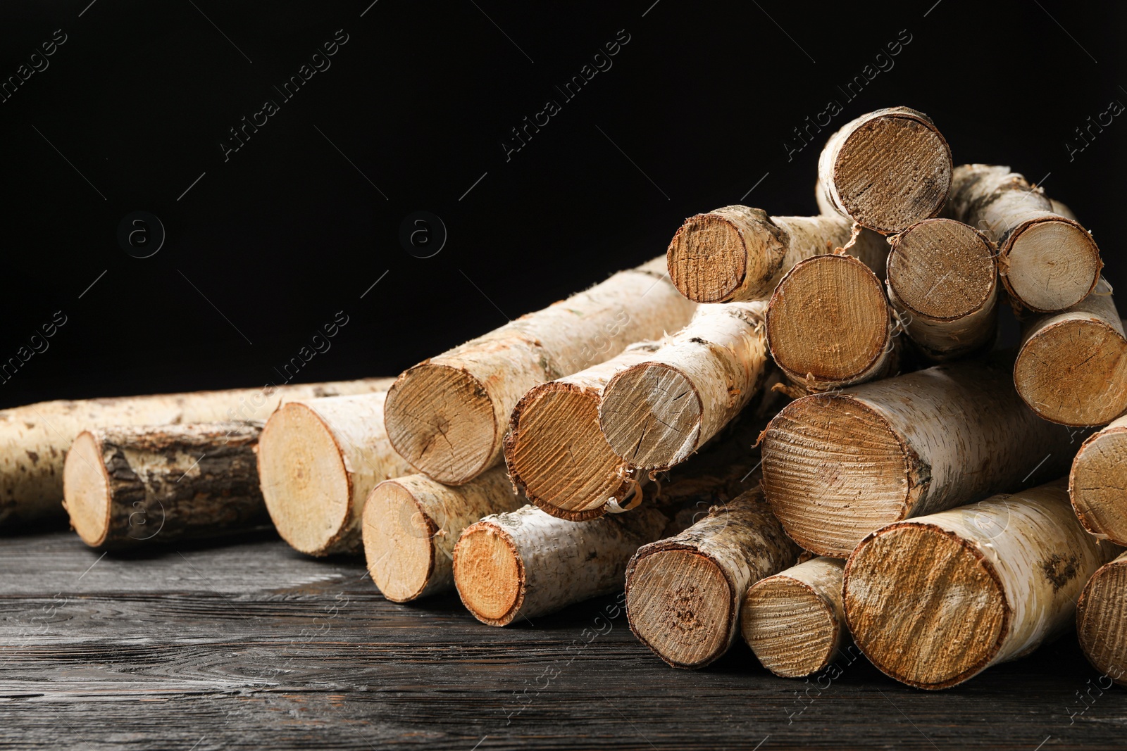 Photo of Cut firewood on table against black background