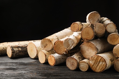 Photo of Cut firewood on table against black background