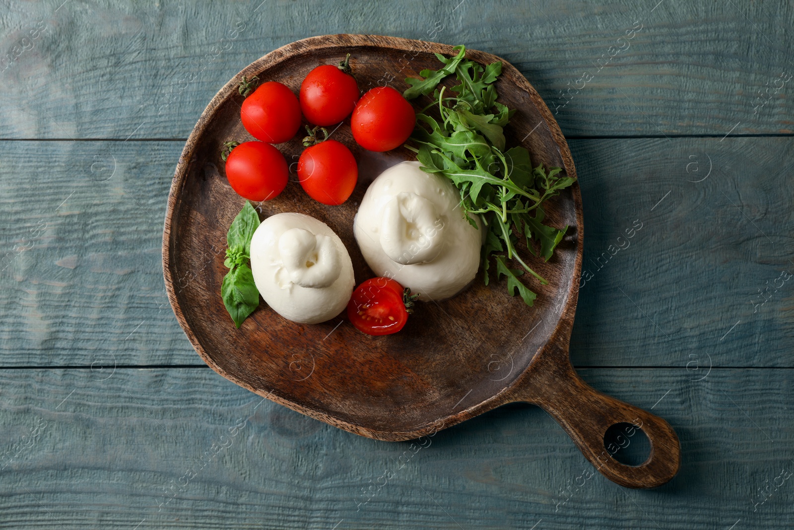 Photo of Delicious burrata cheese with tomatoes and arugula on grey wooden table, top view