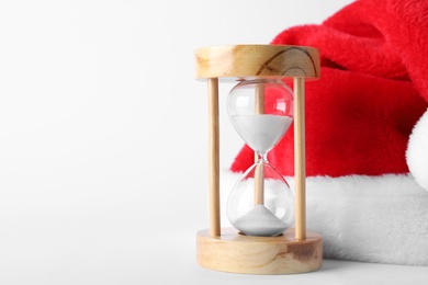 Photo of Hourglass and Santa hat on white background. Christmas countdown