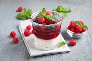 Photo of Delicious panna cotta with berries on grey wooden table