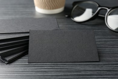 Photo of Blank black business cards on wooden table, closeup. Mockup for design