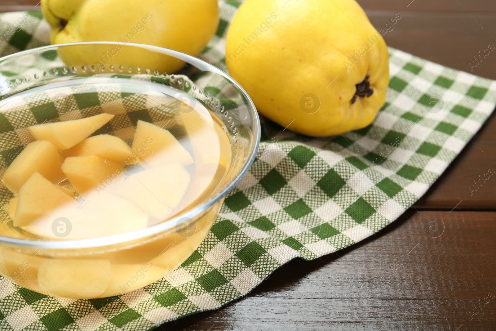 Photo of Delicious quince drink in glass bowl and fresh fruits on wooden table, closeup