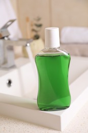 Photo of Fresh mouthwash in bottle on sink in bathroom, closeup