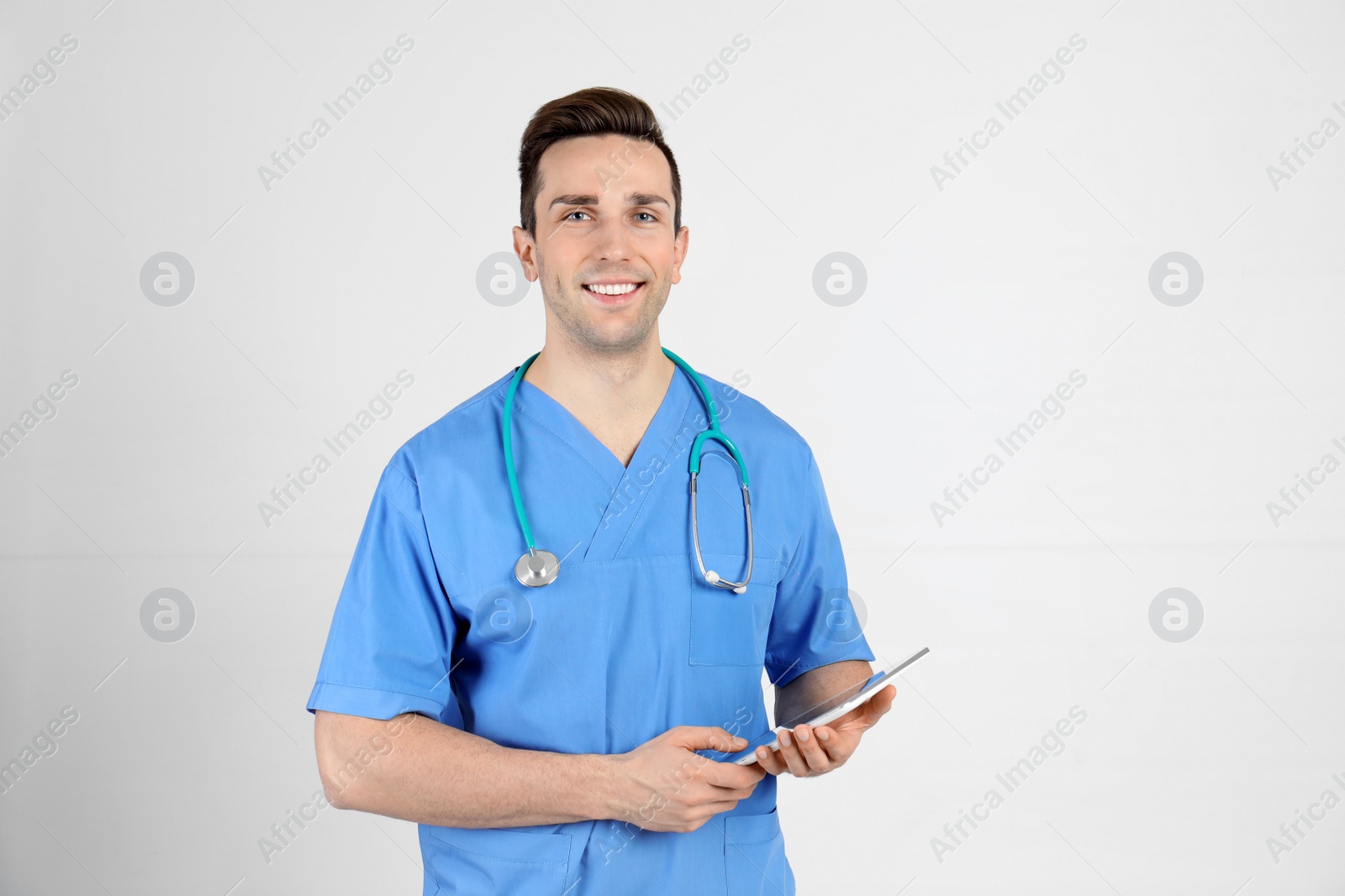 Photo of Portrait of medical assistant with stethoscope and tablet on light background