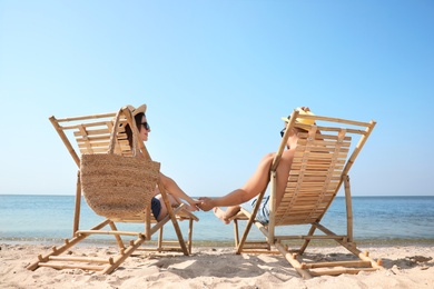 Photo of Young couple relaxing in deck chairs on beach