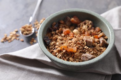 Tasty granola in bowl and napkin on gray table, closeup