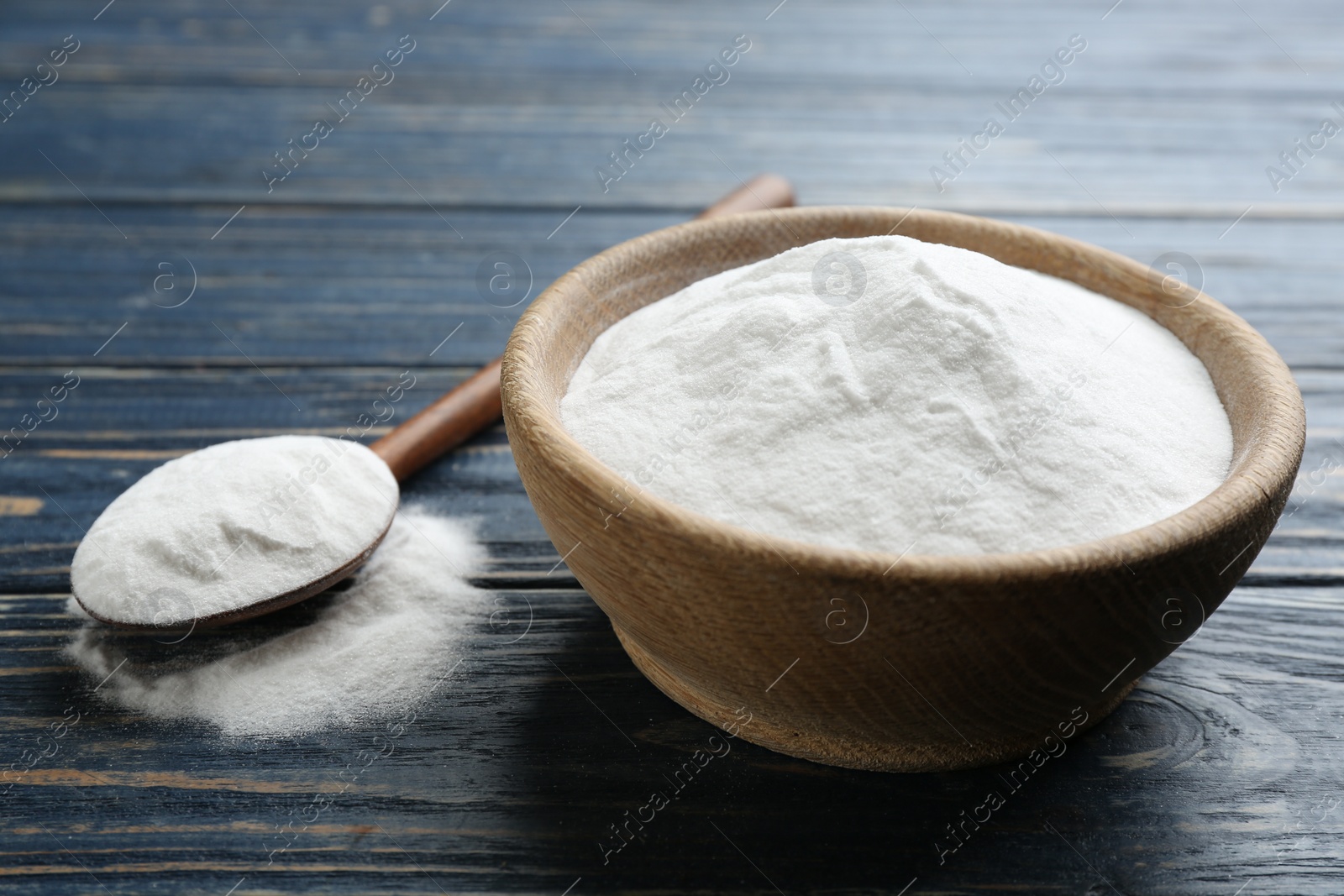 Photo of Baking soda in bowl on blue wooden table