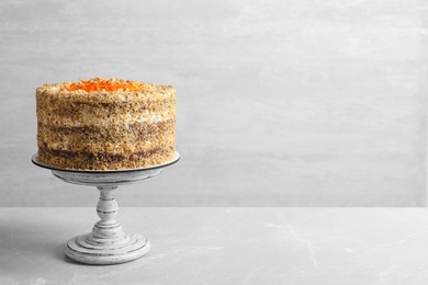 Photo of Sweet carrot cake with delicious cream on grey marble table against light background. Space for text