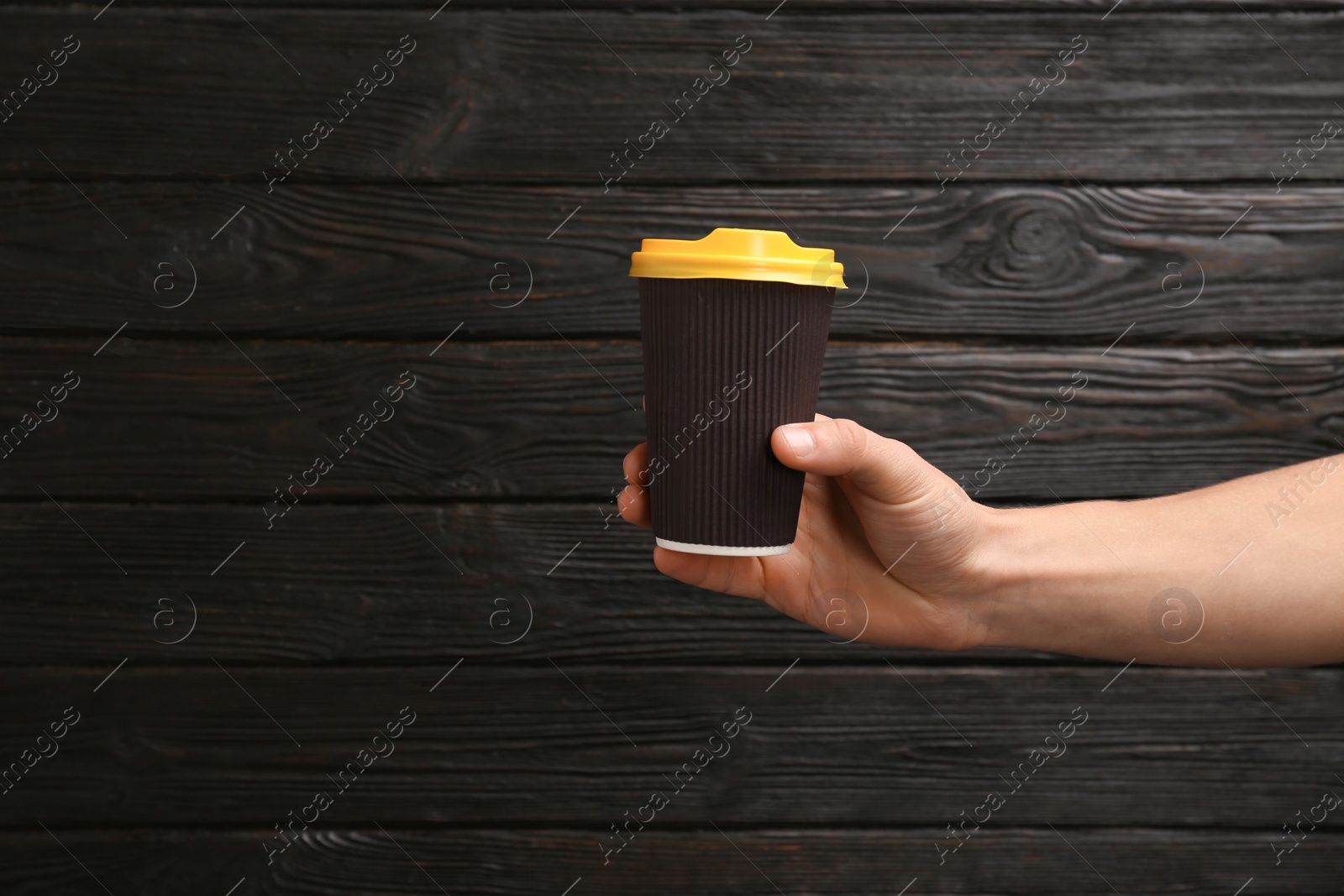 Photo of Woman holding takeaway paper coffee cup on wooden background