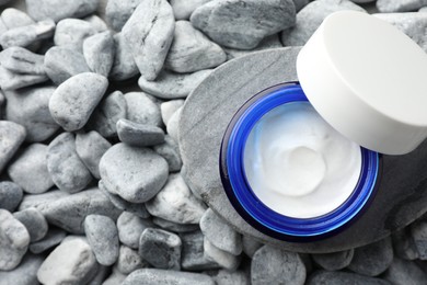 Photo of Jar of moisturizing cream on stones, top view. Space for text