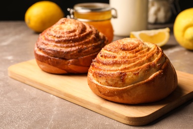 Wooden board with tasty buns on table, space for text. Fresh from oven