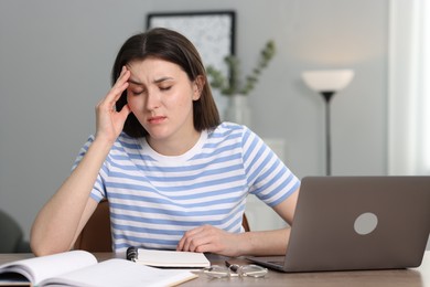 Photo of Overwhelmed woman sitting with laptop at table indoors