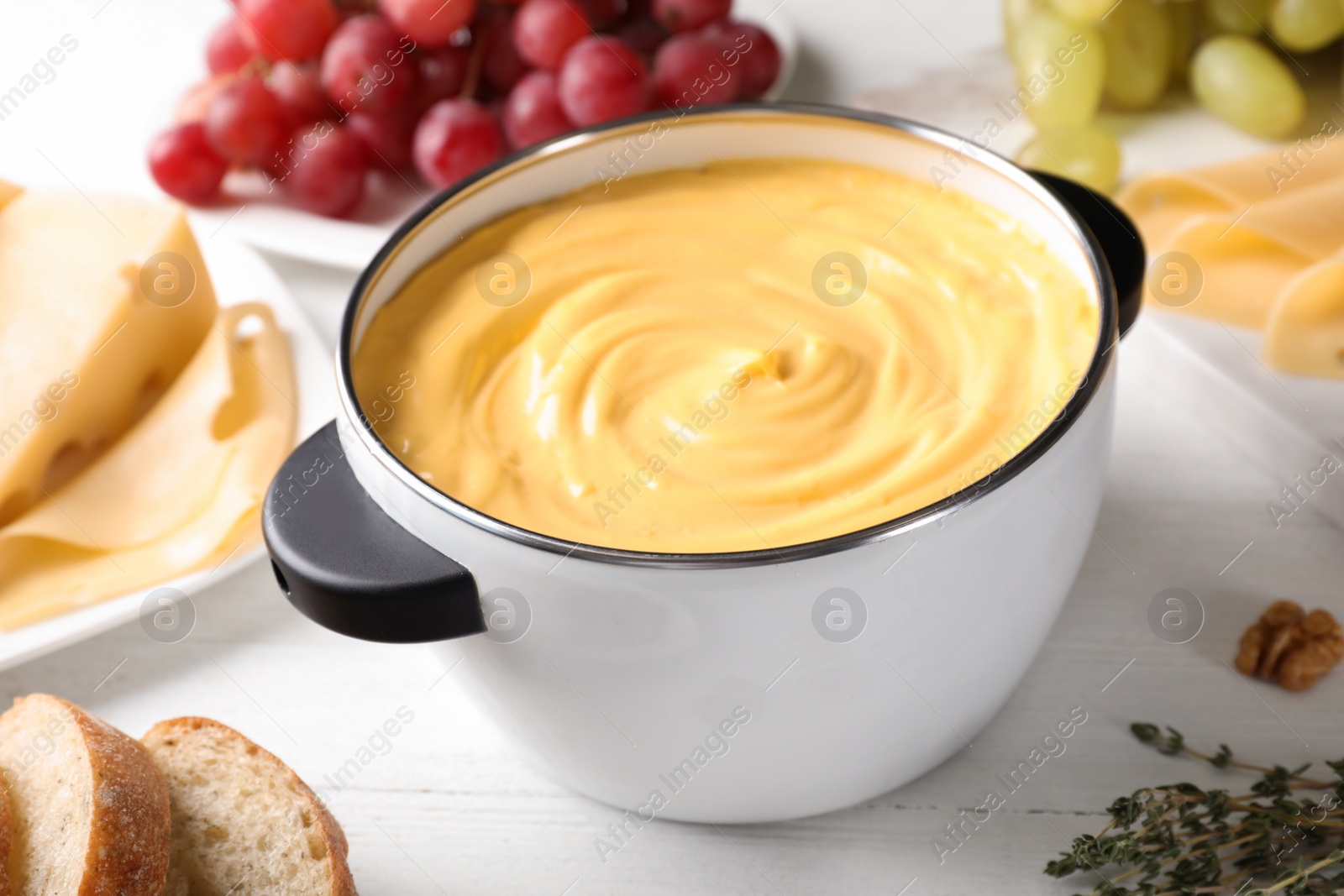 Photo of Pot with delicious cheese fondue on wooden table