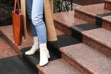 Photo of Woman in stylish leather shoes with bag on stairs outdoors, closeup