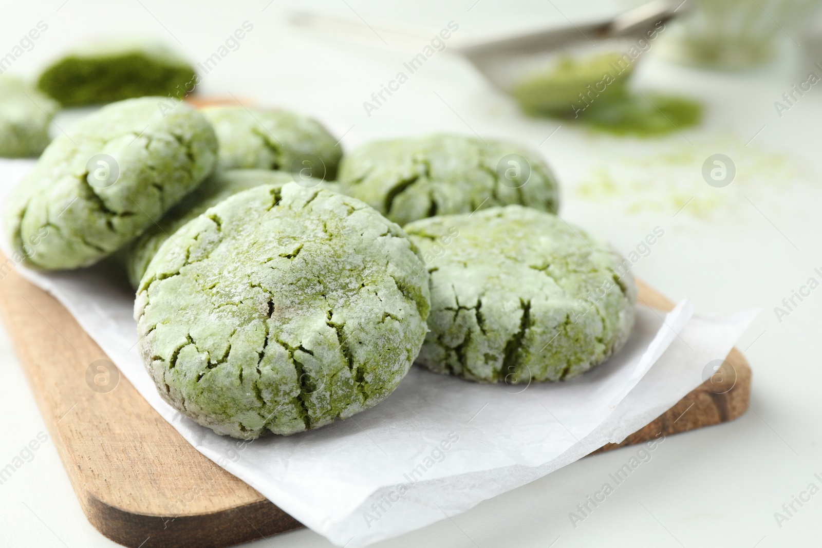 Photo of Board with tasty matcha cookies on white table, selective focus