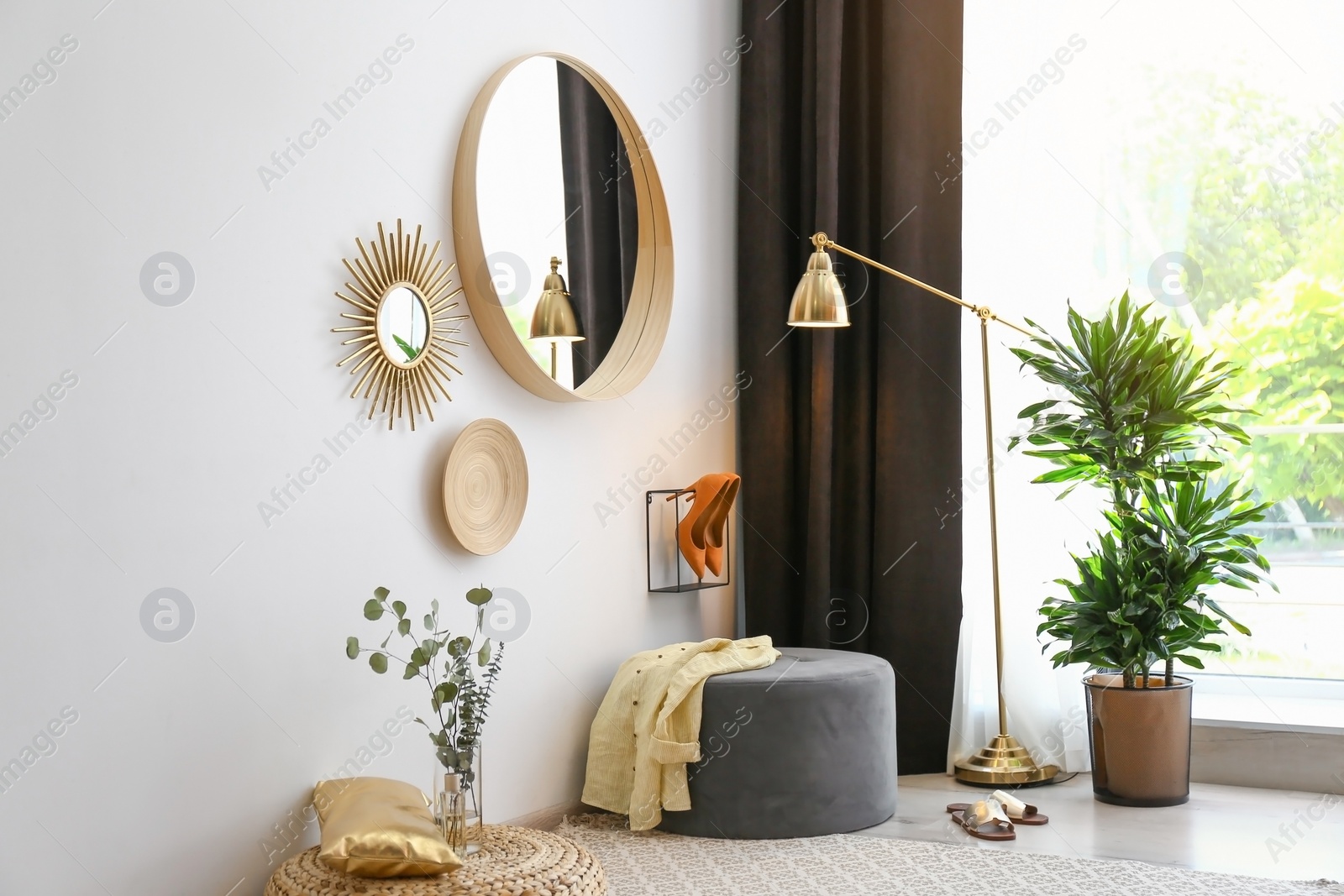 Photo of Hallway interior with big round mirror and ottoman chair near white wall