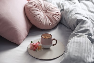 Photo of Aromatic coffee and beautiful flowers on bed with fresh linens