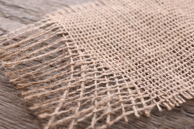Piece of burlap fabric on wooden table, closeup