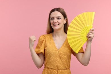 Photo of Happy woman with yellow hand fan on pink background