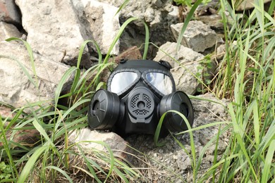 Photo of One gas mask on ground with stones outdoors