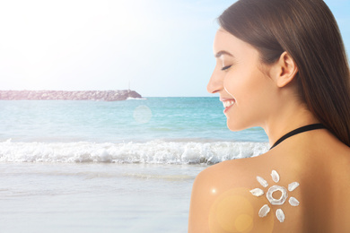 Woman with sun protection cream on her back at beach, space for text