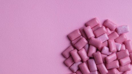 Photo of Heap of tasty sweet chewing gums on pink background, flat lay. Space for text