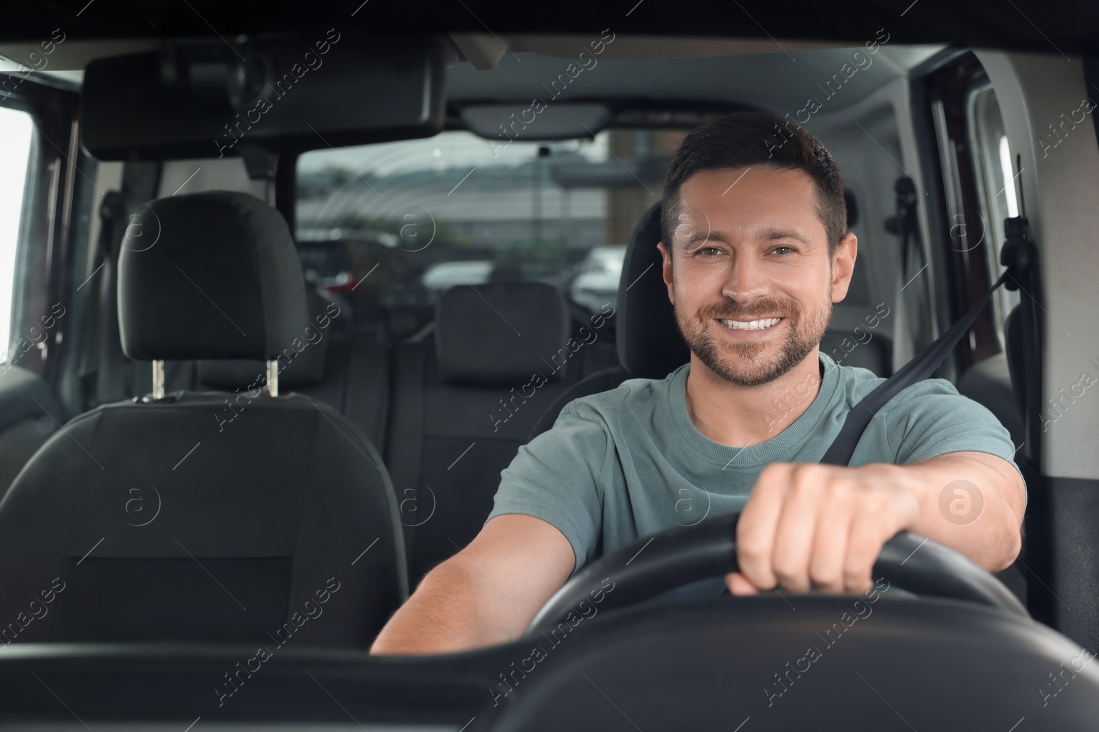 Photo of Listening to radio. Handsome man enjoying music in car, view through windshield