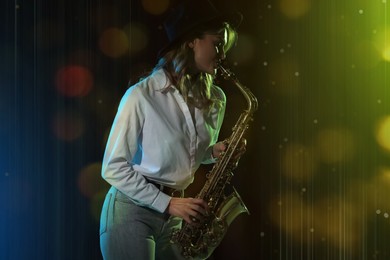 Beautiful young woman playing saxophone on dark background. Bokeh effect