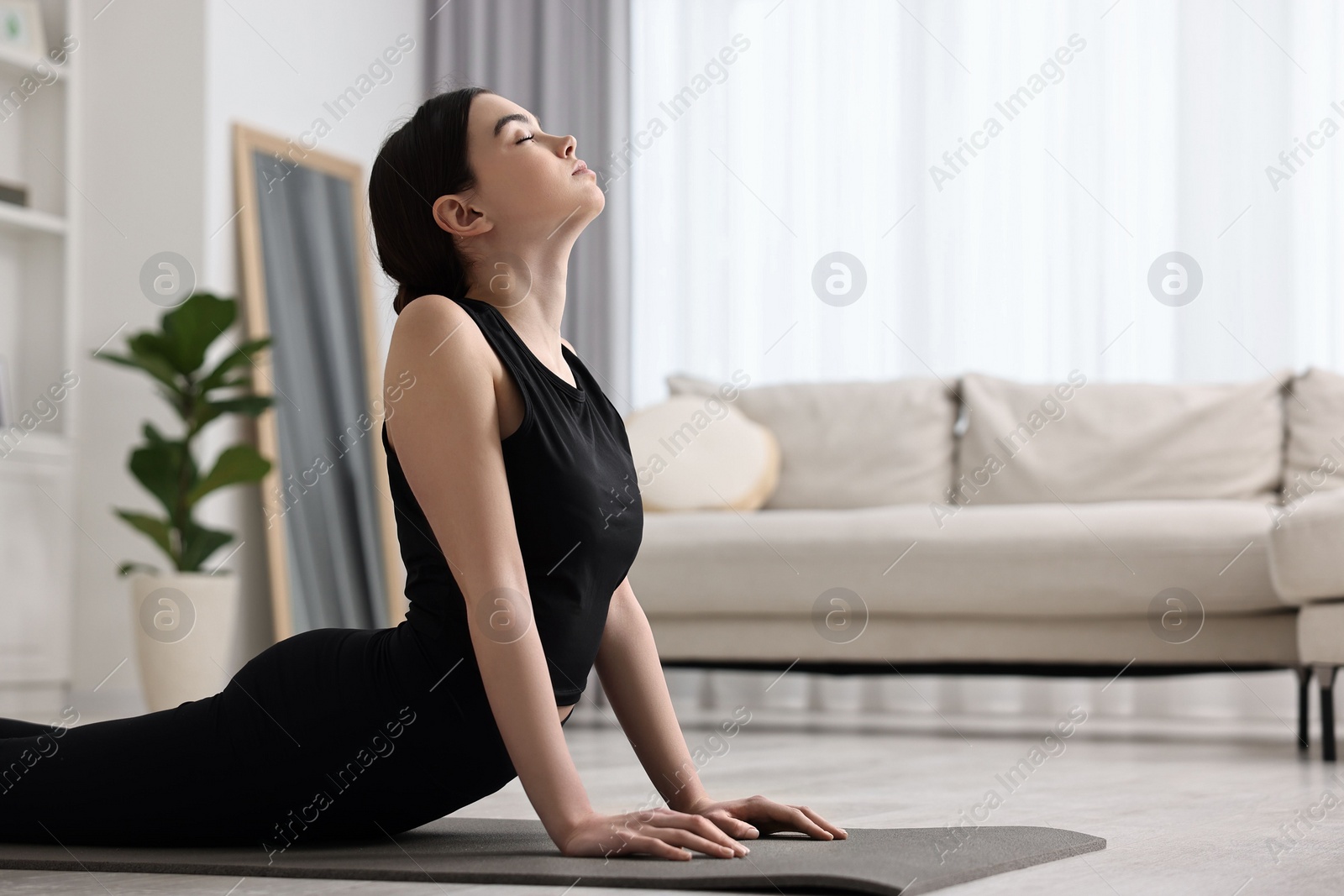 Photo of Girl practicing cobra asana on yoga mat at home. Bhujangasana pose