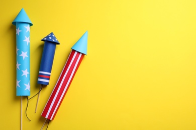 Photo of Firework rockets on yellow background, flat lay with space for text. Festive decor