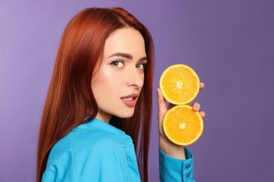 Photo of Beautiful woman with red dyed hair and oranges on purple background