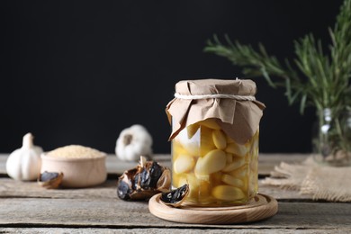 Photo of Garlic with honey in glass jar and fermented black garlic on wooden table. Space for text