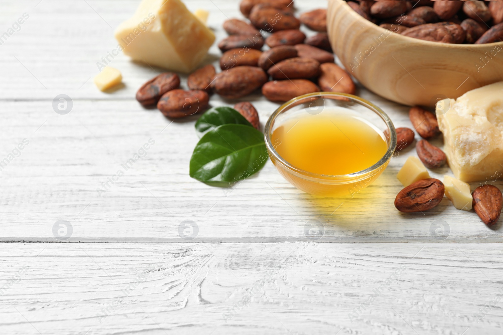 Photo of Organic cocoa butter on white wooden table. Space for text