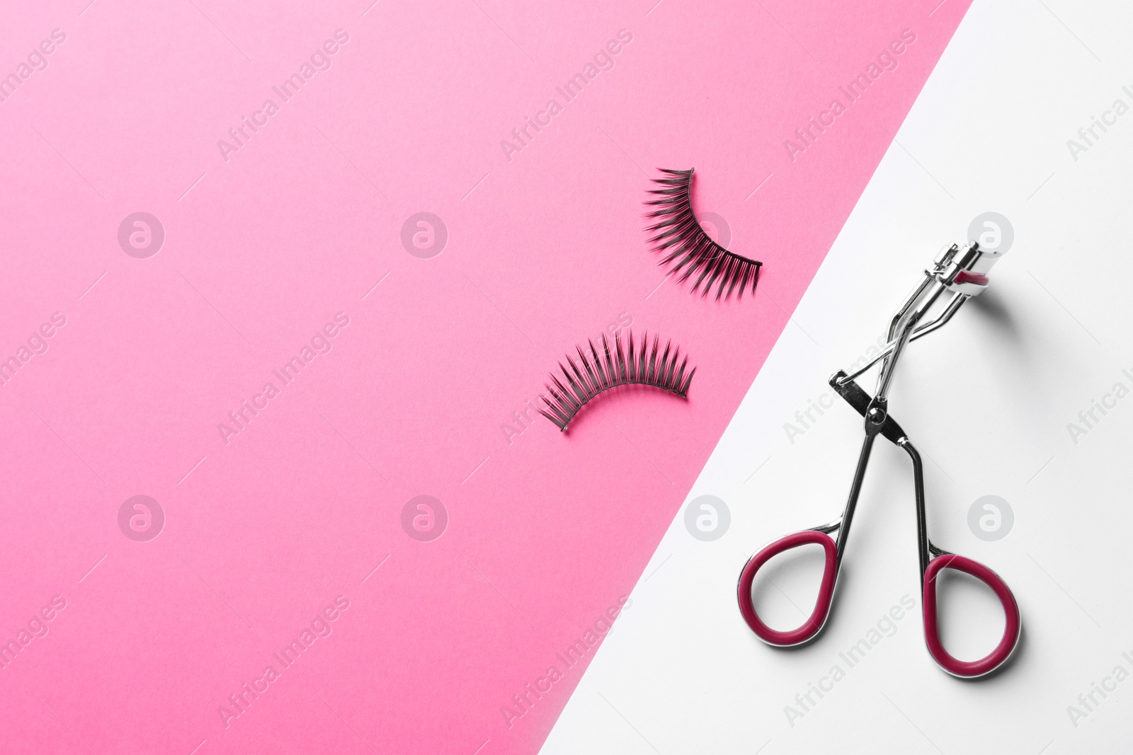 Photo of False eyelashes and curler on color background, flat lay. Space for text