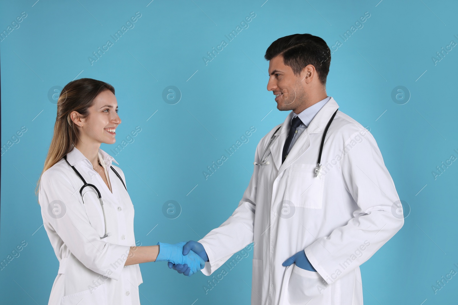 Photo of Doctors shaking hands on light blue background