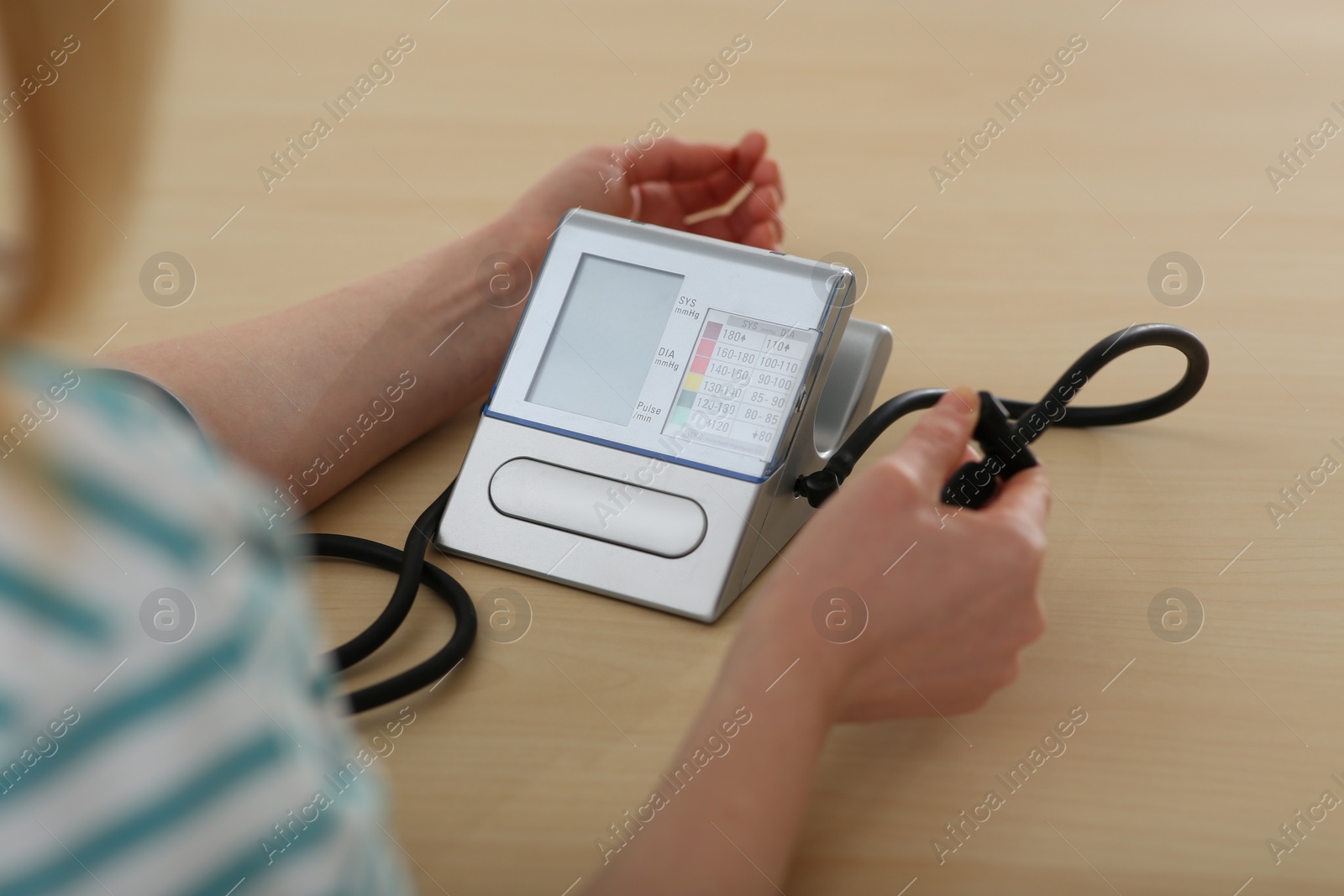 Photo of Woman checking blood pressure at table indoors, closeup