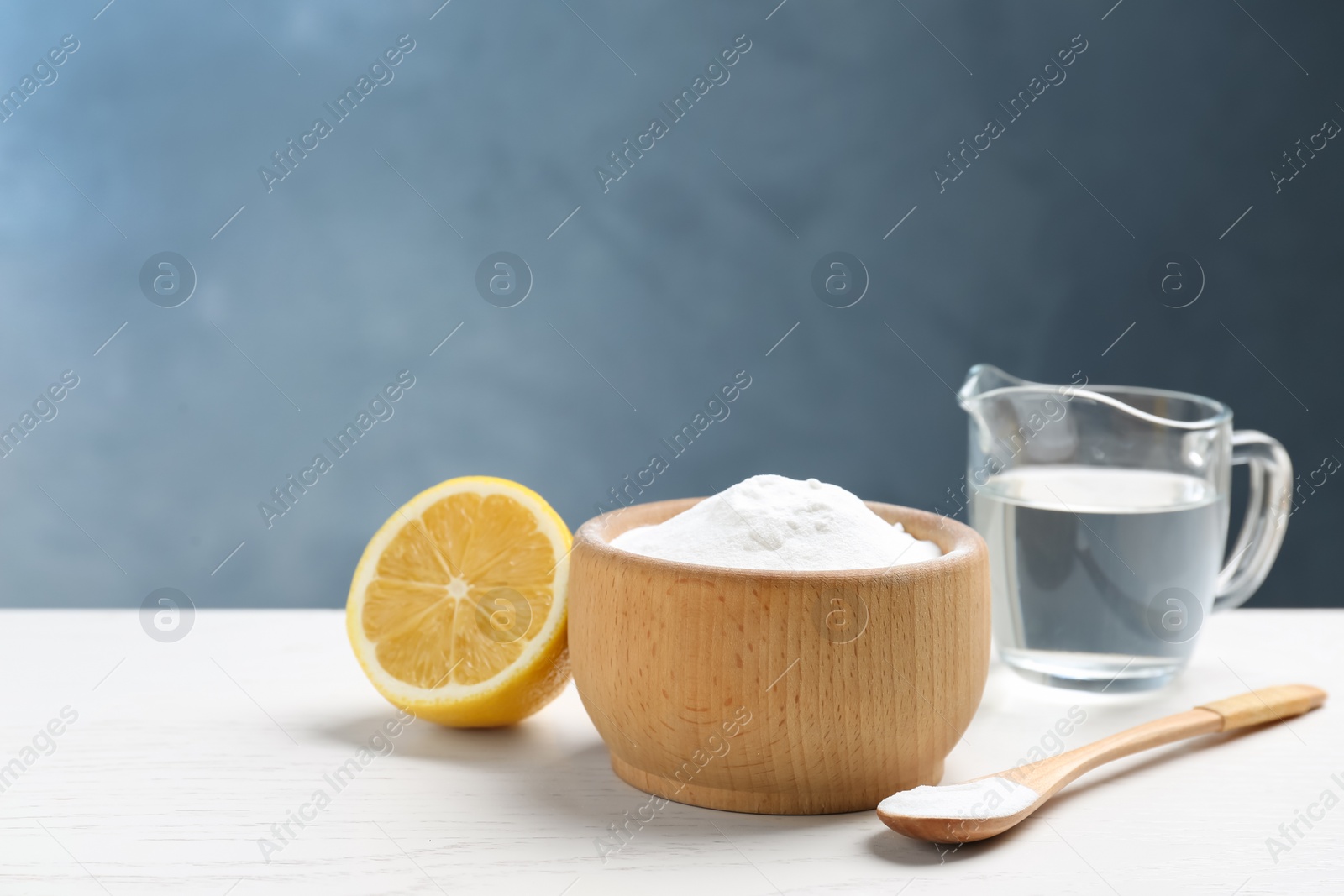 Photo of Baking soda, cut lemon and vinegar on white wooden table