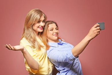 Attractive young women taking selfie on color background