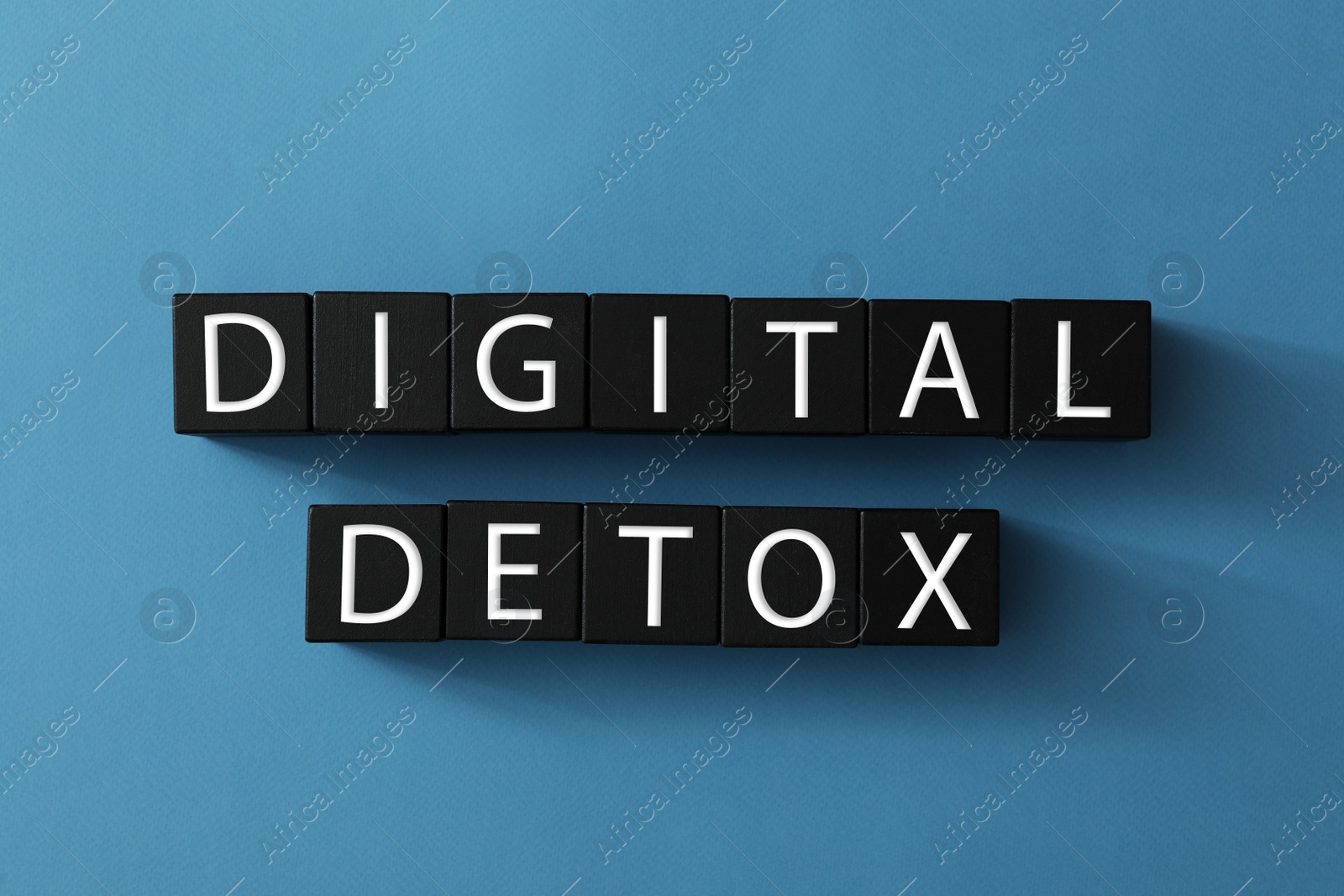 Photo of Black cubes with words DIGITAL DETOX on blue background, flat lay