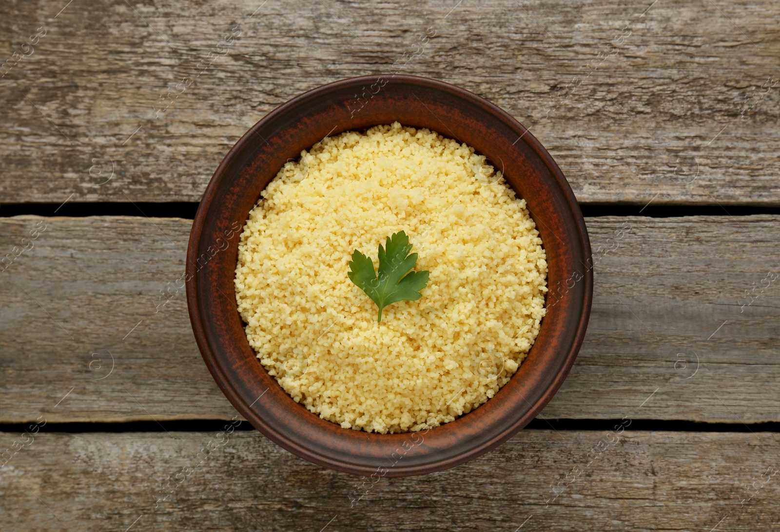 Photo of Tasty couscous with parsley on wooden table, top view