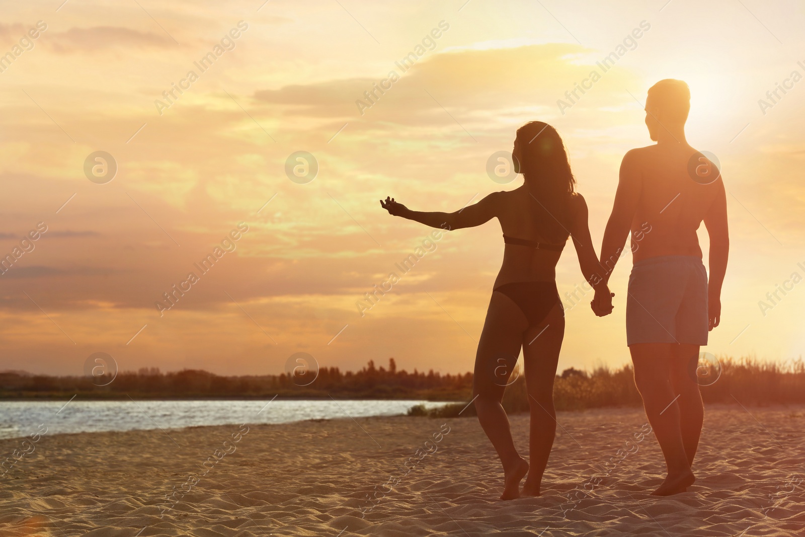 Photo of Young woman in bikini spending time with her boyfriend on beach. Lovely couple