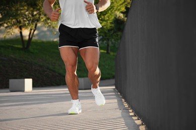 Photo of Man running outdoors on sunny day, closeup