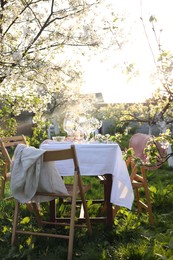 Stylish table setting with beautiful spring flowers in garden